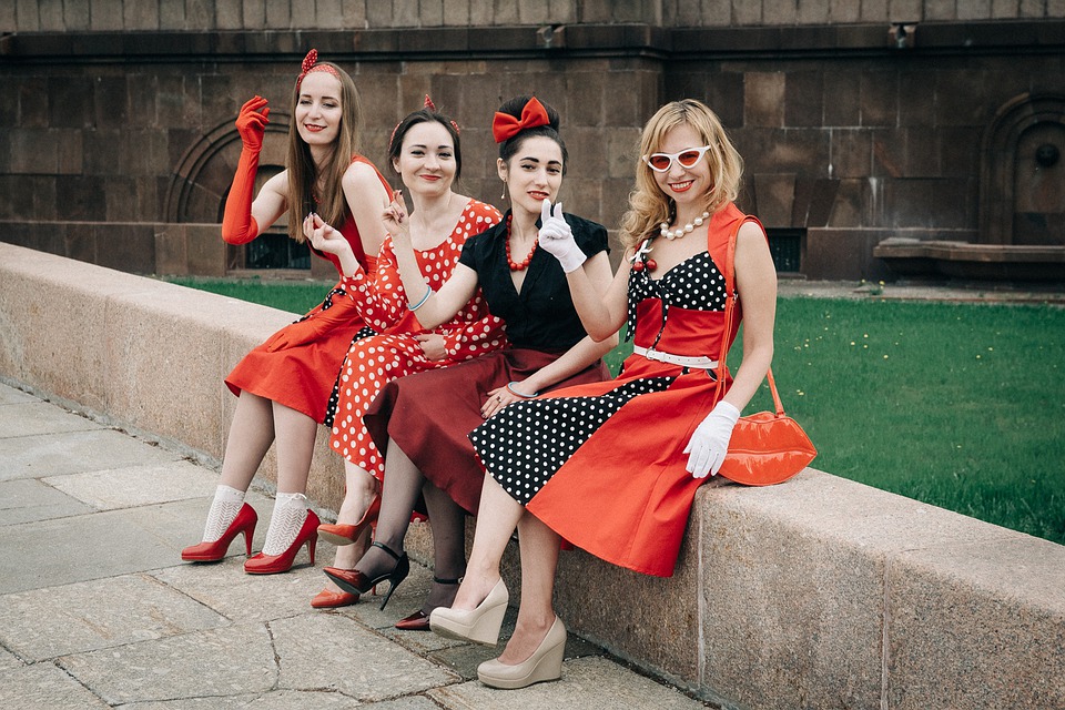 Čtyři ženy oblečené v RETRO stylu. Puntíkové šaty, červené doplňky. 